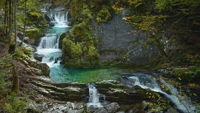 Seamless video loop Cinemagraph of a waterfall river canyon in Bavaria, Germany, close to Tegernsee and Munich on a sunny autumn day. The water is rushing through naturally formed rocks in the forest.