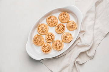 Baking dish with uncooked cinnamon rolls on white background