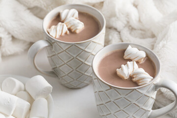 Cups of hot cocoa drink and marshmallows on light background