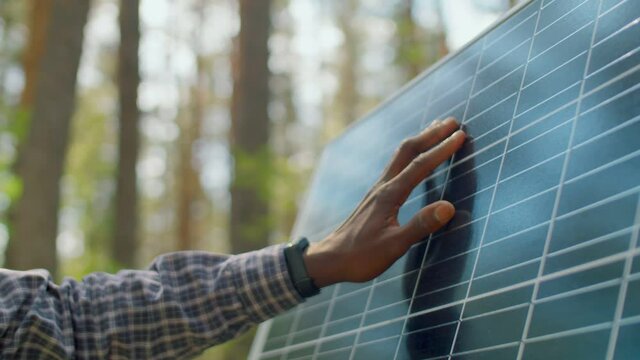 Horizontal close-up slowmo shot footage of unrecognizable Black mans hand touching solar cell panel