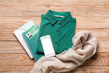 Female clothes, notebooks and smartphone on wooden background