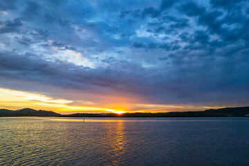 Sunrise waterscape with colourful cloud covered sky