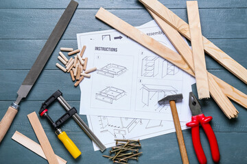 Furniture assembling instructions and tools on blue wooden background