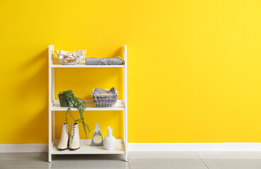 Modern shelving unit with wardrobe organizers near yellow wall