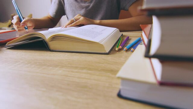 Close up and candid 4K of working woman who is reading a book concentratively on table with stacks of books as foreground shows concept of learning knowledge from self studying lifestyle. 