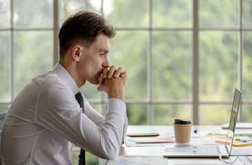 Unhappy upset stressed depressed Caucasian businessman sitting holding hands on head having headache. Employee tired exhausted because working overtime. Male staff officer worn out due to overwork