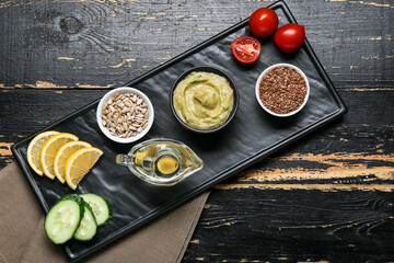 Board with tasty baba ghanoush and products on dark wooden background
