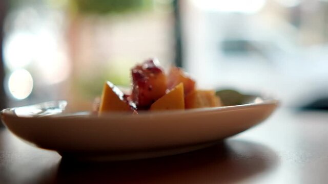 Plate of chopped mango with Mexican chamoy sauce and blurry background