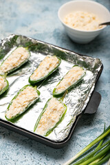 Frying pan with uncooked jalapeno poppers on color background