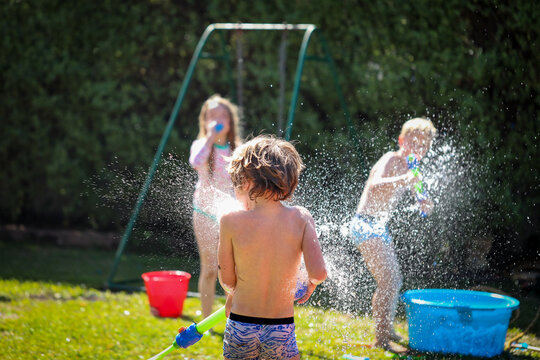 Kids Enjoying Backyard Water Fight In Summer