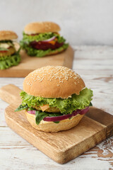 Wooden board with tasty vegetarian burger on table