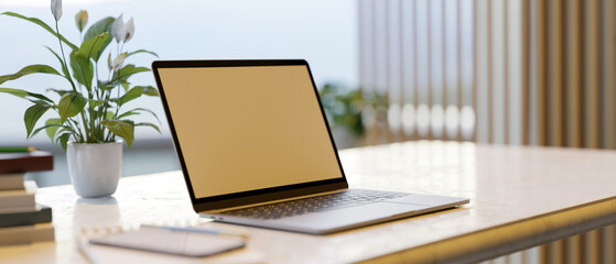 Mockup of a laptop computer screen on a desk with home decor in a modern workspace