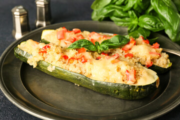 Plate with quinoa stuffed zucchini boats on dark background