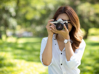 Female photographer taking photo with vintage or retro camera in a park