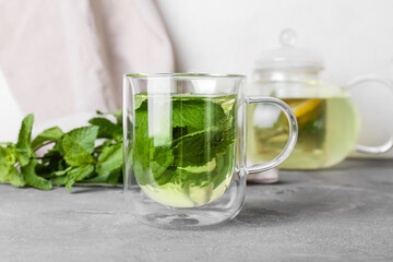 Glass cup of tasty mint tea on table, closeup