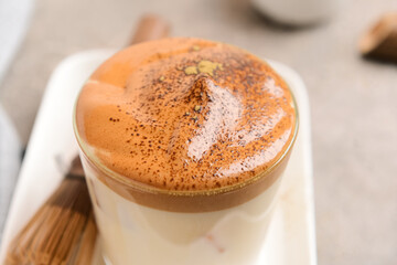 Glass of tasty dalgona hojicha latte on grey background, closeup