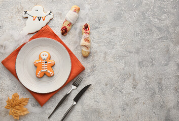Stylish Halloween table setting with cookies and decor on grunge background