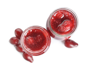 Jars of tasty dogwood jam and berries on white background