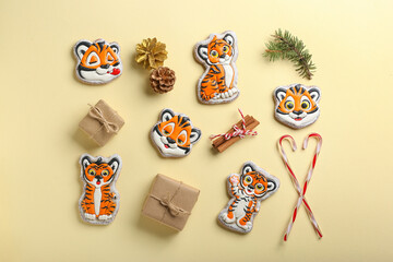 Cute cookies in shape of tiger, gifts and New Year decor on color background