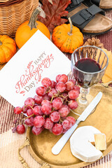 Tray with delicious food, glass of wine and card with text HAPPY THANKSGIVING DAY on plaid, closeup