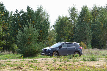 Fototapeta na wymiar Toyota RAV 4 modern SUV on a dirt country road against the background of an autumn forest
