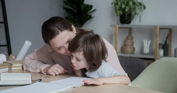 Attractive young mother studying with her kid pupil at home and teaching him how to count and write. Learning logic and math skills together in homeschooling. Female tutor teaching a preschooler