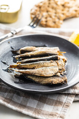 Smoked sprats on plate. Canned sea fish.