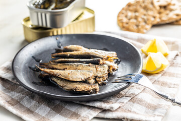 Smoked sprats on plate. Canned sea fish.