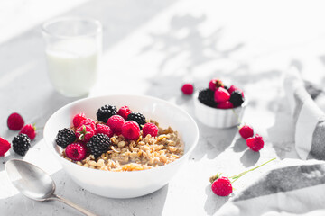 Breakfast bowl with granola, muesli, raspberry, blackberry on gray table