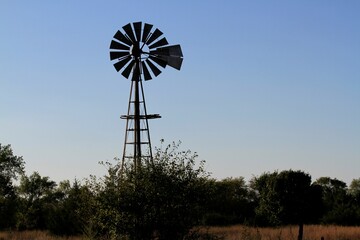 windmill at Sunset with a colorful sky and tree's north of Hutchinson Kansas USA out in the country.