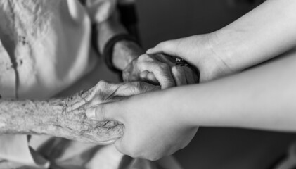 Young woman hand touch and hold an old woman's wrinkled hands