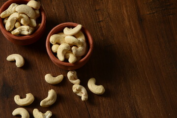 Fototapeta premium Roasted salted raw cashew nuts in wooden bowl on rustic table, healthy vegetarian snack, Cashews on white background, Cashews nut background, Bowl with cashew nuts