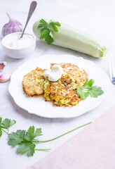 Delicious zucchini pancakes with garlic-yogurt sauce on a light background.