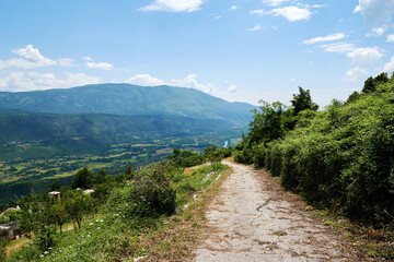 A beautiful rural road on the mountains slope with a peak in the background. Summer mountains landcape backgrounds
