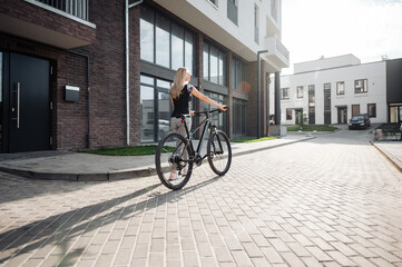 Back view of sporty woman walking with bike at urban area