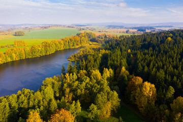 View from drone of forest landscape around picturesque lake on sunny autumn day