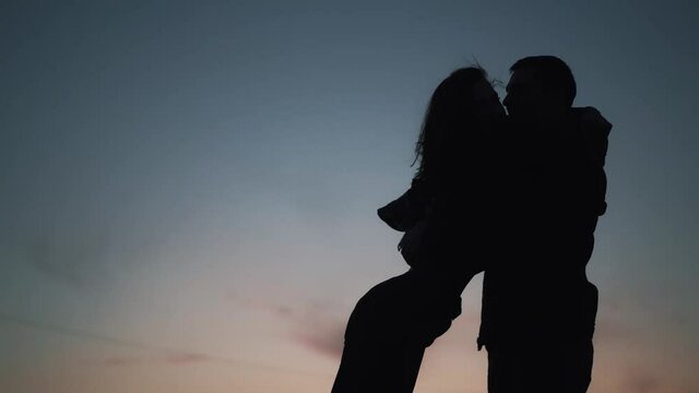 Slowmotion of dark silhouettes man meets his girlfriend and hug. Lovers miss each other and finally met together to hug and kisses. Concept of love and freedom. High quality FullHD footage