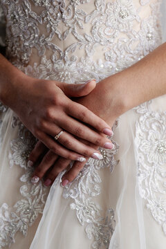 Hands of the Hands of the bride close-up on the background of the wedding dress. Vertical orientation 
