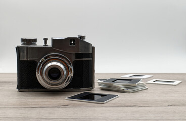 Retro photo camera with slides on wooden table.