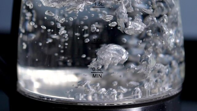 Rapid boiling water in a clear glass kettle, slow motion, close up