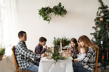 A large family has a festive Christmas breakfast or dinner in the living room decorated with New...