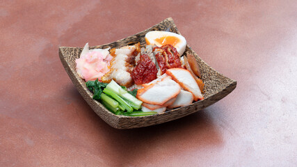 Rice crispy pork and Roasted pork and roast duck with egg. on from natural coconut pattern. arranged on an orange tiled floor.