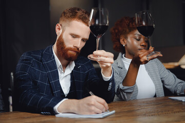 Sommeliers man and woman tasting red wine and making notes at degustation notepad