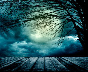 Old grunge wooden table in front of scary night scene. Halloween composition background with scary...