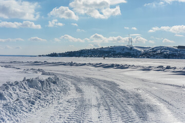 Car tracks in the snow go into the distance. Wheel tracks on a snow road.