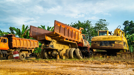 Obraz premium Wreck of heavy machinery in the junkyard of forestry company. Broken old rusty truck and excavator