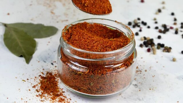 Chef taking with teaspoon spices ground red pepper or chili from glass spice jar.