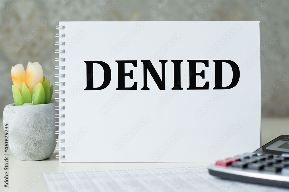 Poster denied text on a notebook that stands on the table next to the calculator