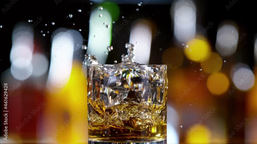 Poster super slow motion of falling ice cube into whiskey drink, camera motion. speed ramp effect. filmed o