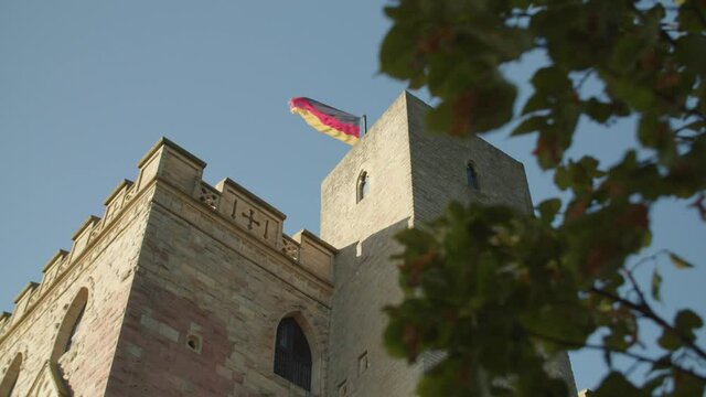 Low Angle Shot of Tower of Hambach Castle through Leaves on Brunch and Blue Sky with German Flag